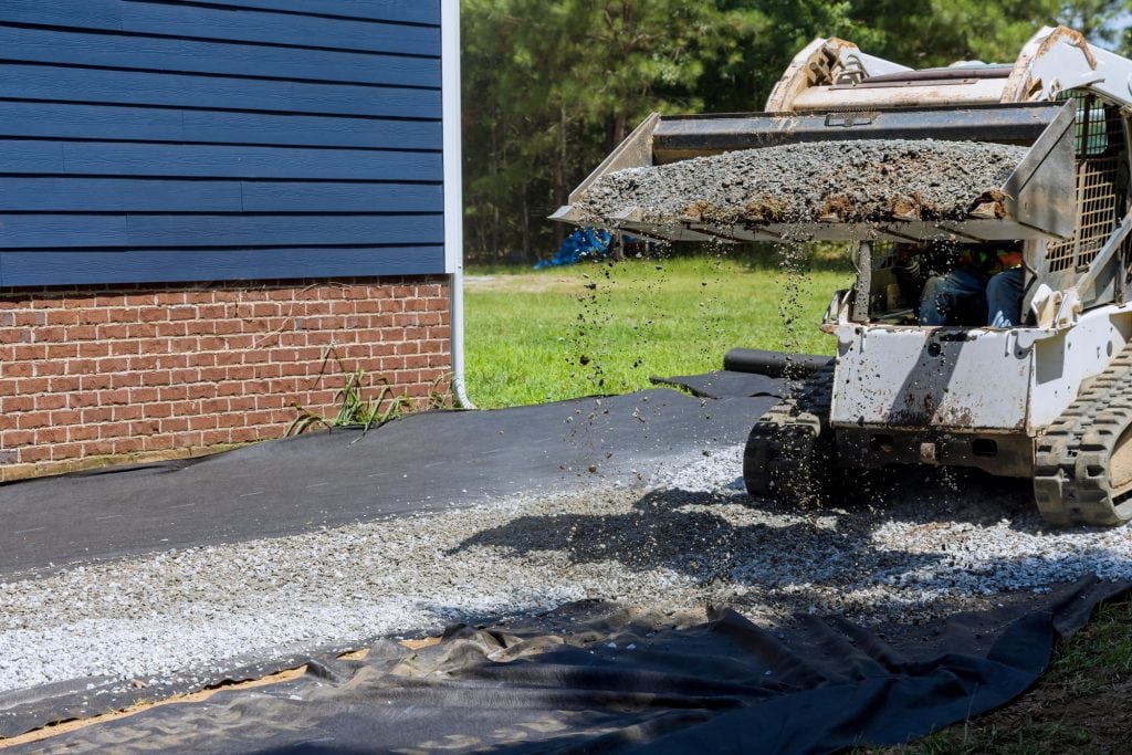 Tractor has uploaded gravel preparation platform on which storage shed will be installed near house
